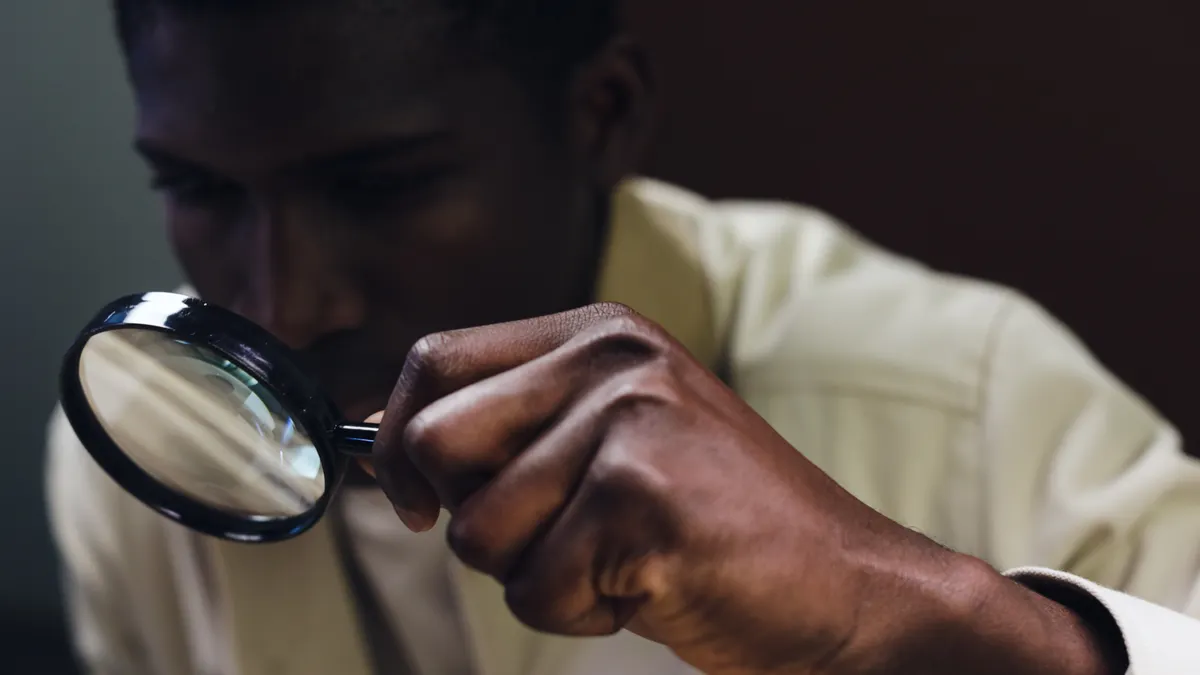 person examining something closely with a magnifying glass