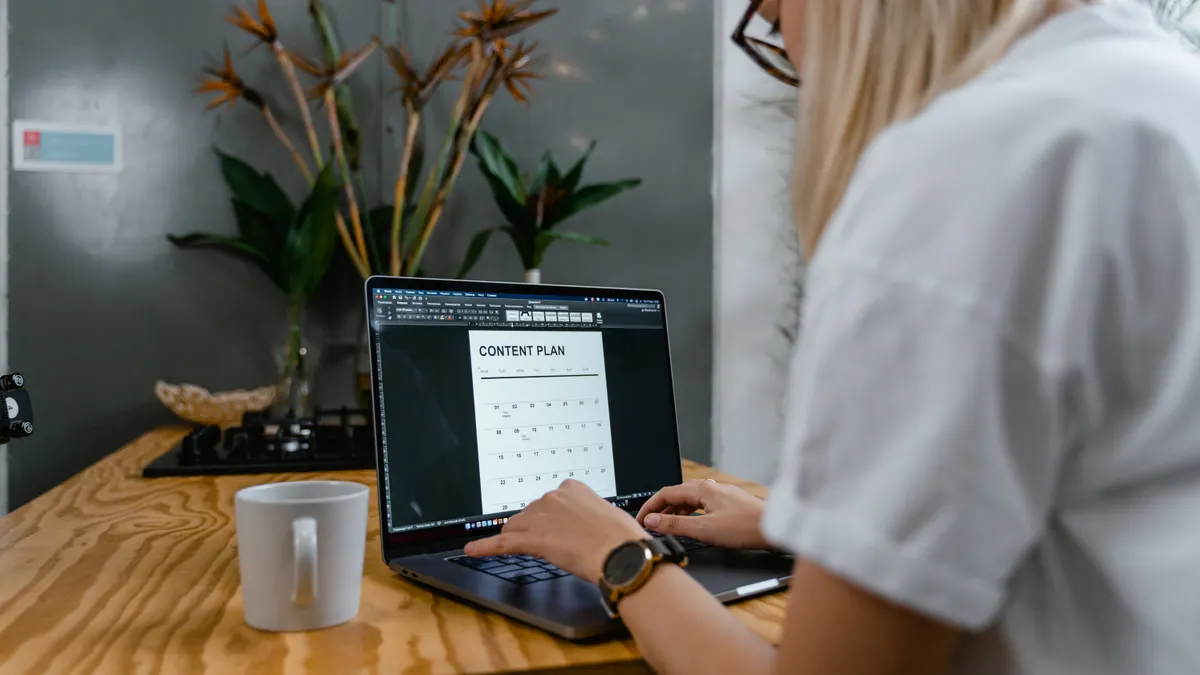 Person using a laptop with a content plan on screen
